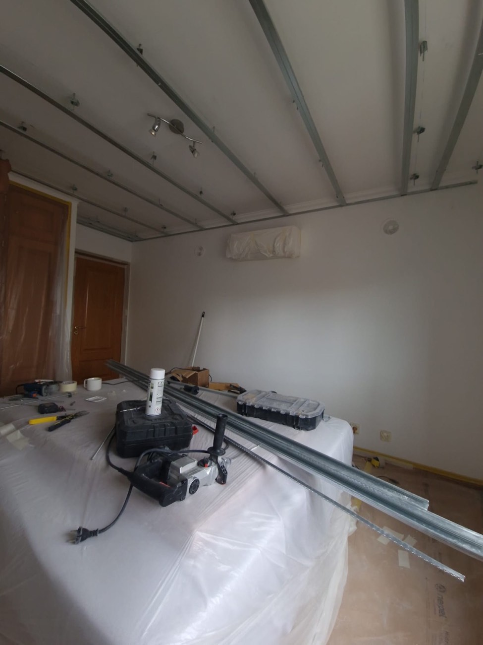 Quarto com móveis tapados com plástico durante a montagem do teto